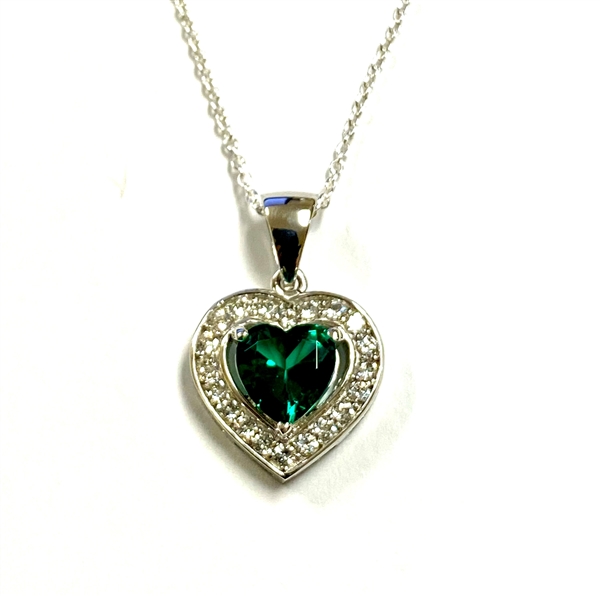 Heart shape Emerald Essence stone in prong setting, is surrounded by round brilliant Diamond Essence stones, making another heart. 2.5 cts.t.w. in Platinum Plated Sterling Silver.