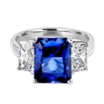 Sapphire Ring - 4.0 Cts. Radiant Emerald cut Saphhire Essence in center accompanied by Radiant Emerald cut Diamond Essence on sides. 5.0 Cts. T.W. set in Platinum Plated Sterling Silver.