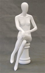 Female egghead mannequin in seated pose. Her legs are crossed with her hands on her lap.