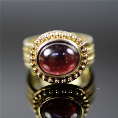 Sultry Sovereign Ring photo. This is a very royal design, The 18k yellow gold really combines well with the round, center red rhodolite creating a Sultry Sovereign. The details are little dots and braided designs on the sides.