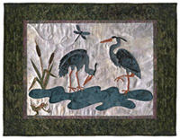 Quilt block of two herons near a stream being watched by a frog and a dragonfly.