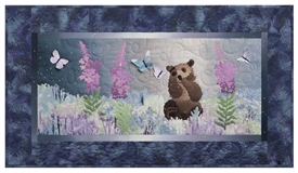 Quilt block of a brown bear cub playing with butterflies in a field of wildflowers.