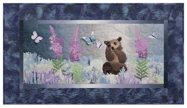Quilt block of a brown bear cub playing with butterflies in a field of wildflowers.