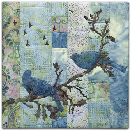 Quilt block with stylized birds on a tree branch and flying in blue and pink floral patterns