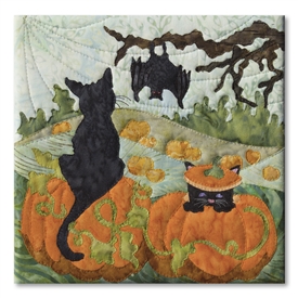 Quilt block of two black cats in a pumpkin patch, with a bat hanging from a tree and the large moon behind.