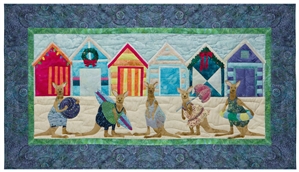 Quilt block of five kangaroos ready to play on the beach, in front of brightly colored beach huts decorated for the holidays.