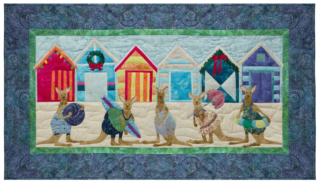 Quilt block of five kangaroos ready to play on the beach, in front of brightly colored beach huts decorated for the holidays.