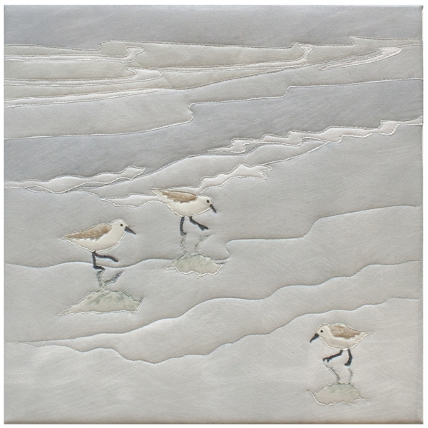 Quilt block of sandpipers looking for food on a beach.