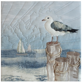 Quilt block of a seagull perched on a post overlooking the ocean to get the best perspective.