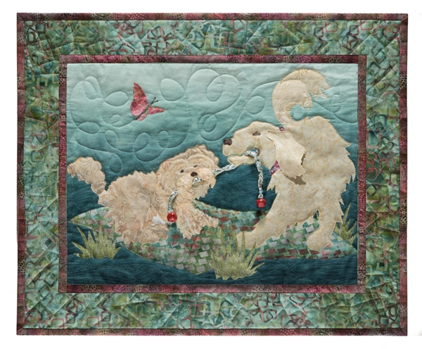 Quilt block of two dogs playing tug-of-war over a rope toy, on a picnic blanket.