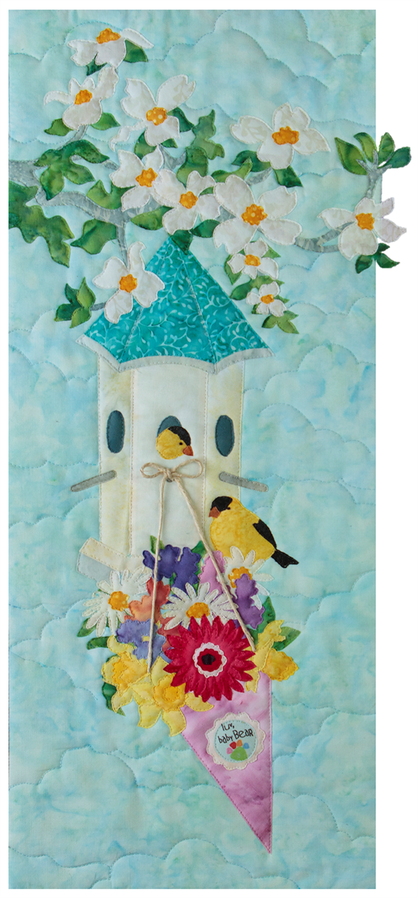 A bird house hanging on a flowering tree branch, with a bouquet of beautiful, colorful flowers hanging off the front. Two small yellow birds are sitting on the flowers and in the bird house.