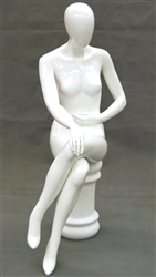 Female egghead mannequin in seated pose. Her legs are crossed with her hands on her lap.
