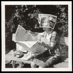 Relaxing in the park with her home made sun hat.  Ironic that the pictures on the hat are fashion photos.  Historical Black and White Photo Postcard