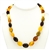 Natural Baltic Amber Cherry, Custard, Light and Dark Honey Amber Oval Amber Beads  Graduated sizes up to .75" long by .6" wide bronze colored cord w/ knot between each bead. Silver claw clasp closure.