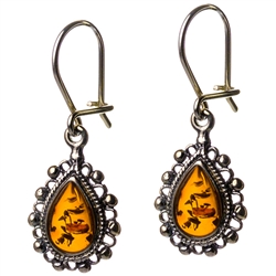 Artistic antique tear drop shaped silver earrings with a center of honey colored amber. Approx 1" long.