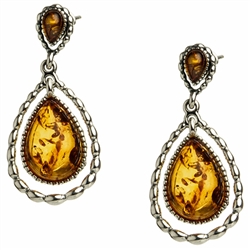 Artistic antique oval shaped silver earrings with a center of honey colored amber. Approx 1" long.