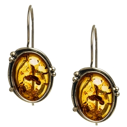 Artistic antique oval shaped silver earrings with a center of honey colored amber. Size approx 1.25" x .6".