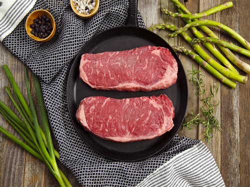 Two New York Strip steaks in a cast iron skillet.