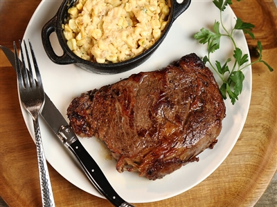 A personal-sized crock of Rube's creamy jalapeno corn alongside a perfectly grilled ribeye.