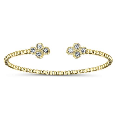 This simple cuff features a thin band of 14k yellow gold with diamonds centered in a cluster settings.