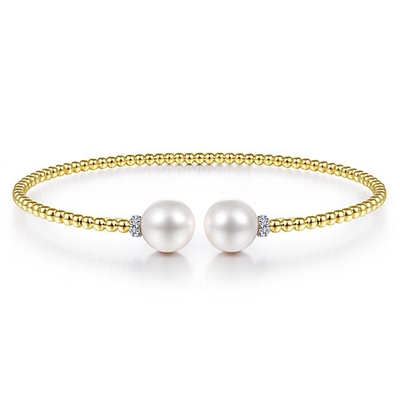 This 14k yellow gold bangle features pearls and diamonds.