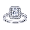 An emerald cut center diamond gleams magnificently encircled in round brilliant diamonds set in a vintage halo engagement ring designed by Gabriel & Co.