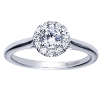A sleek white gold band leads up to a round diamond halo engagement ring with a round center diamond already included!