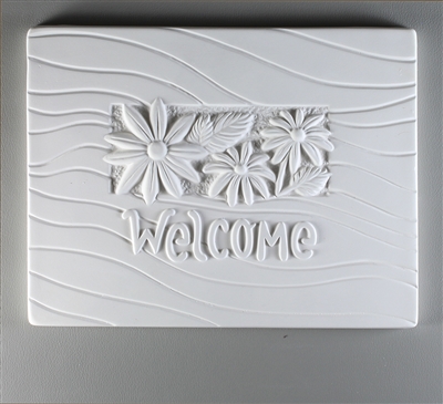 A rectangular tile made of white ceramic with a carved design. The center has a smaller rectangle filled with three daisy-like flowers and leaves. Below the flowers is curving text saying Welcome. The rest of the tile is filled with gentle waving lines.