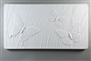 A long rectangular tile made of white ceramic. The carved texture on it shows three butterflies in front of a background of curving lines suggesting grass. Two of the butterflies are larger in the foreground, and there is one smaller one between them.