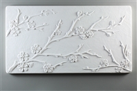 A long rectangular tile made of white ceramic. The carved texture has three delicate branches of cherry blossoms. One branch begins midway up the left edge, the largest branch begins from the bottom left, and another small branch is in the bottom right.