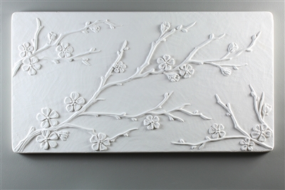 A long rectangular tile made of white ceramic. The carved texture has three delicate branches of cherry blossoms. One branch begins midway up the left edge, the largest branch begins from the bottom left, and another small branch is in the bottom right.