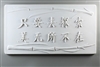 A long rectangular tile made of white ceramic. The carved texture has Chinese characters in the middle with two stalks of bamboo bordering them, one above and one below. The text roughly translates to beauty is everywhere as long as you look for it.