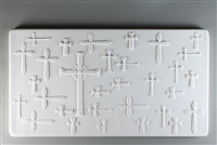 A long rectangular tile made of white ceramic. The carved texture has many shapes and sizes of cross, all relatively simple in design. The crosses are either upright or turned left-to-right. The largest cross is just left of center and has more detail.