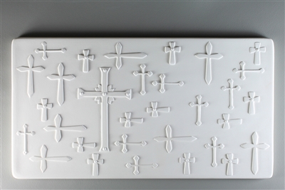 A long rectangular tile made of white ceramic. The carved texture has many shapes and sizes of cross, all relatively simple in design. The crosses are either upright or turned left-to-right. The largest cross is just left of center and has more detail.