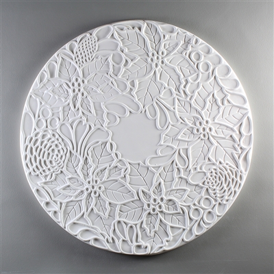 A circular tile made of white ceramic. The carved texture has a ring of five poinsettia flowers with additional leaves and pinecones surrounding the edges, leaving a small circle in the very center of the tile empty and blank.