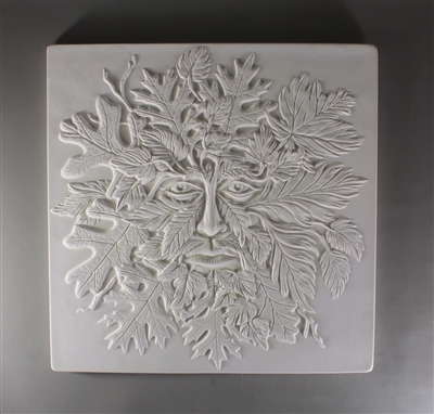 A large square tile made of white ceramic. The carved texture has the details of a manâ€™s face in the center emerging from a cluster of leaves and other foliage.