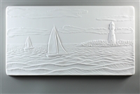 A long rectangular tile made of white ceramic. The carved texture shows a seascape with two sailboats on the waves. There is a peninsula to their right with a lighthouse, and the sky above them has a few long, wispy clouds.