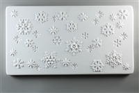 A long rectangular tile made of white ceramic. The carved texture has different sizes and shapes of snowflakes scattered around it. Some are carved into the texture while others stand out.