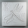 A large square tile made of white ceramic. The carved texture is occupied mostly by a single large dragonfly in the center. There are three lily pads visible in the space around the dragonfly, and the one in the top left has a lotus flower.