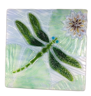 A decorative glass square with a dragonfly design. The central dragonfly is a vibrant green with bright blue eyes. The three lily pads surrounding it are a light green, and the lotus flower in the top right corner is a soft purple and red.
