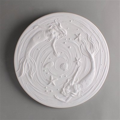 A circular tile made of white ceramic. The carved texture has two mermaids swimming around the edge, with a scattering of starfish and shells between them. There are gently raised waved lines around them that spiral towards the center.