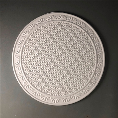 A circular tile made of white ceramic. The carved texture has a center circle of a repeating small diamond pattern that mimics old crystal. The ring outside this center circle has half-circle embellishments along it before reaching the tileâ€™s border.