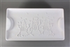 A rectangular white ceramic mold for fusing glass on a grey background. The edges are slightly raised, and there is a raised half circle at either end. The center has been carved with three snowmen in top hats and scarves amidst a snowy scene.