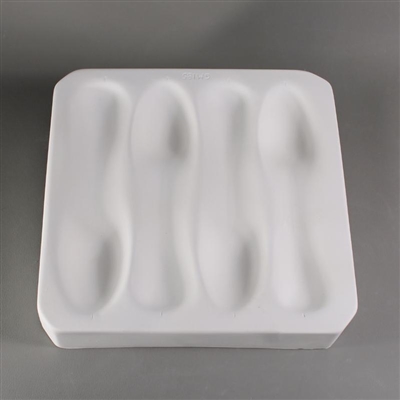 A rectangular white ceramic mold for fusing glass on a grey background. The impressions of four separate spoons have been carved into it. They alternate directions to save space. The bowls and ends are carved in, and the handles are slightly raised.