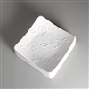 A square white ceramic mold for fusing glass on a grey background. Each corner of the square curves slightly upwards. The mold has been carved with four simplistic flowers spaced out into a diamond and surrounded by small oval leaves and raised dots.