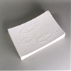 A rectangular white ceramic mold for fusing glass on a grey background. Each corner curves slightly upwards. The mold has been carved with the simple outlines of three long fish resembling trout or salmon. Each fish has a few raised dots as bubbles by it.