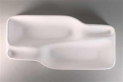 A white ceramic mold for fusing glass on a grey background. Two cavities shaped like bottles facing opposite directions have been carved into it. The sides have a gradual slope, and there is a thin raised wall separating the two bottles.