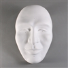 A white ceramic mold for fusing glass on a grey background. The mold has been carved into the shape of a human face with raised features.