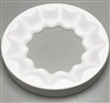 A circular white ceramic mold for fusing glass on a grey background. A scalloped circle has been cut out of the center. A larger scalloped circle surrounds it, and the edges of the larger circle slope downwards to meet the edges of the empty center.