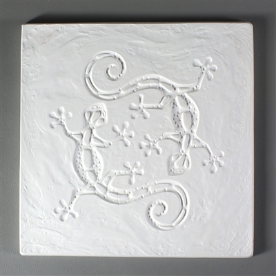 A square tile made of white ceramic for texturing hot glass. The tile has been carved with a top-down view of two geckos circling the center. The geckos have been stylized into a more geometric design, and the background behind them is lightly textured.